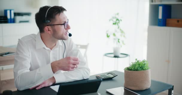 Genç Işadamı Ofiste Masasında Kalem Dijital Tabletle Otururken Kulaklıkla Konuşuyor — Stok video