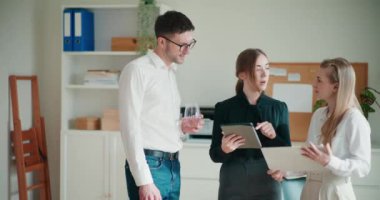 Genç iş kadını şirket ofisinde iş arkadaşlarıyla görüşürken dijital tablet üzerinde tartışıyor.