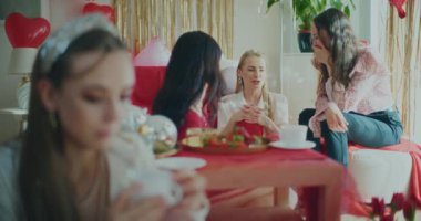 Galentines Günü 'nde evde bayan arkadaşlarıyla konuşan mutlu genç bir kadın.