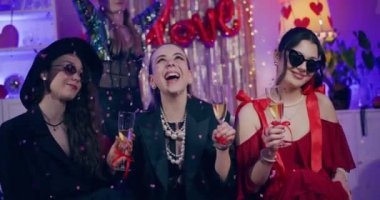 Apartmandaki Galentines günü partisinde şampanyayla mutlu genç bayan arkadaşlar.