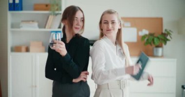 İş yerinde sırt sırta duran gülümseyen genç bayan girişimcilerin portresi.