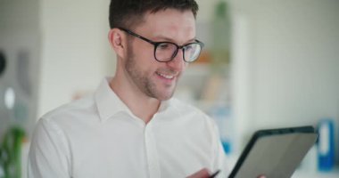 Şirket işyerinde çalışırken dijital tablet kullanan gülümseyen genç girişimci