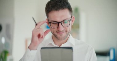 Şirketin çalışma alanında dikilirken dijital tablet kullanan kendine güvenen genç işadamı