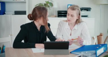 Şirket ofisindeki toplantı sırasında dijital tablet üzerinde tartışan genç bayan meslektaşlar strateji planlarken