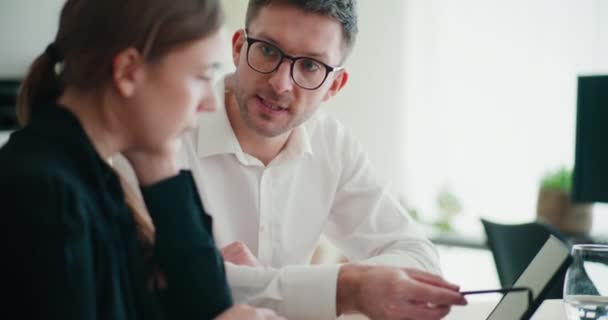 stock video Confident young businessman and businesswoman discussing strategy over digital tablet while sitting at desk in office