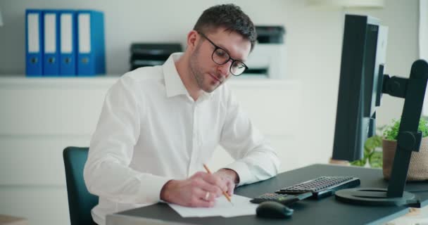 Ofisteki Bilgisayar Masasında Kağıt Üzerine Yazarken Bütçeyi Hesaplayan Kendinden Emin — Stok video