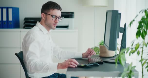 Ofisteki Bilgisayar Masasında Otururken Bütçeyi Hesaplayan Stresli Genç Girişimci — Stok video