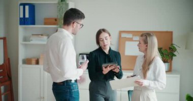 Şirket işyerindeki toplantı sırasında planlama stratejisi sırasında belge ve dijital tablet üzerinde tartışan genç meslektaşlar