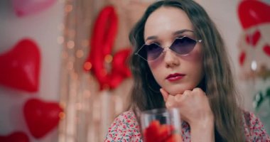 Galentines gününde, elleri çenesinde güneş gözlüklü, düşünceli, çekici bir genç kadın.