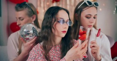 Galentines Günü 'nde elinde yemek ve dekorasyon tutan güneş gözlüklü şık genç bir kadın.