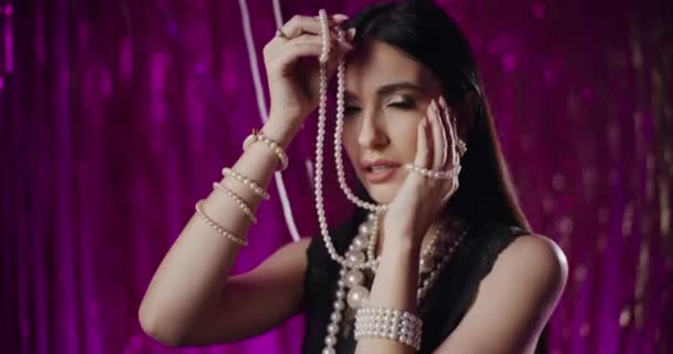 装飾の前に真珠のネックレスを保持する魅惑的なファッショナブルな若い女性の肖像画 — ストック動画
