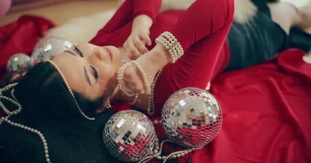Yatakta Disko Toplarının Yanında Yatarken Inci Kolye Tutan Seksi Genç — Stok video