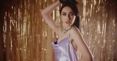 Siyah eldivenli baştan çıkarıcı genç kadın parlak flama dekorasyonunun önünde poz veriyor.