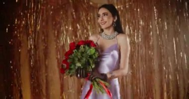 Neşeli, çekici genç bir kadın elinde parlak süslemelere karşı bir demet taze kırmızı gül tutuyor.