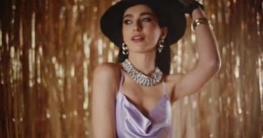 Siyah eldivenli ve şapkalı çekici genç bir kadın parlak flama dekorasyonunun önünde poz veriyor.