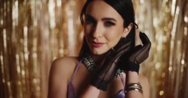 Siyah eldivenli çekici bir kadın. Parlak flama dekorasyonunun önünde poz veriyor.