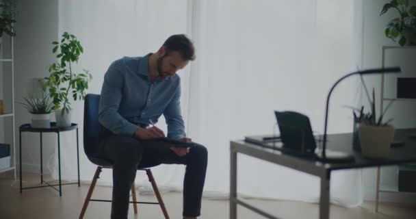 自信を持って若い男性起業家は 企業のワークスペースで椅子に座っている間 スタイラスでデジタルタブレットで戦略を書く — ストック動画