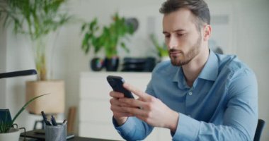 Genç yakışıklı işadamının ofiste otururken cep telefonuyla mesajlaşırken çekilmiş kareleri.