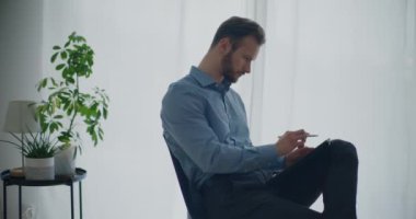Stylus 'la dijital tablet üzerinde şirket işyerinde otururken kendine güvenen genç sakallı iş adamı stratejisi yazıyor.