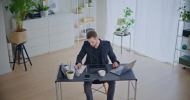 Şirketin çalışma alanında dizüstü bilgisayarla otururken kağıt üzerinde kendinden emin bir iş adamı stratejisi yazıyor.
