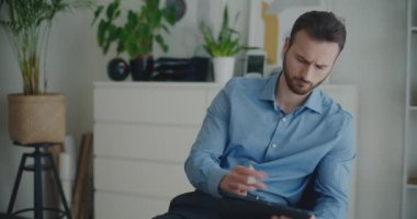 Düşünceli genç yakışıklı iş adamı şirket işyerinde otururken Stylus 'la dijital tablet üzerine strateji yazıyor.
