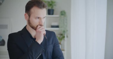 Yakışıklı genç işadamı, şirket işyerinde siyah iş kıyafetleri içinde dururken elinde kalem beyin fırtınası stratejisi tutuyor.