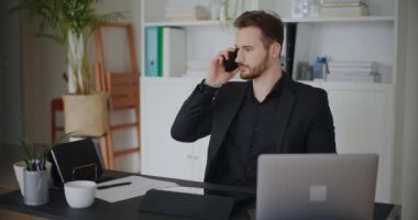 Yakışıklı genç işadamının telefon görüşmelerine cevap verirken ve şirket çalışma alanında çalışırken iyi haberler dinlerken kareye kapatılmış görüntüleri.
