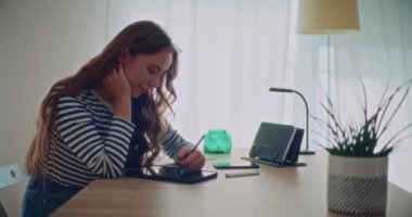 Evde otururken, Stylus 'la dijital tablete yazı yazan çekici, genç kadın esmerin yan görüntüsü