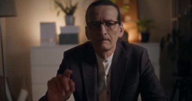 Ofiste geç saatlere kadar çalışırken gözlük çıkaran kıdemli iş adamının portresi.