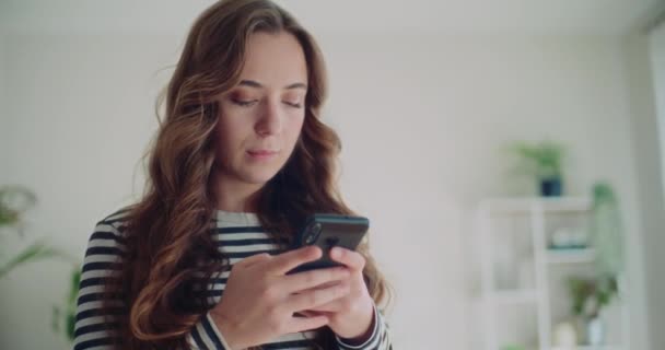 Evdeki Oturma Odasında Akıllı Telefondan Sosyal Medyada Gezinen Güzel Genç — Stok video