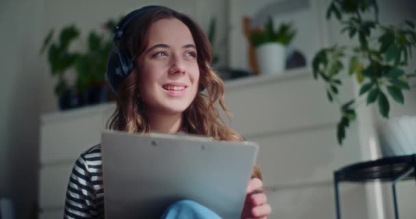Smiling Pretty Young Woman Drawing Clipboard While Listening Music Headphone — Stok Video