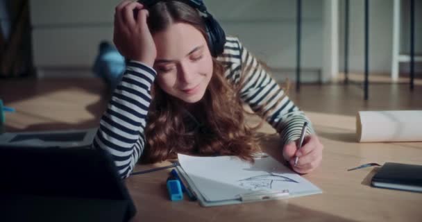 Sonriente Joven Atractiva Mujer Escuchando Música Mientras Dibuja Portapapeles Acostado — Vídeos de Stock