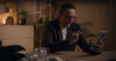 Üst düzey erkek yönetici, ofiste geç saatlere kadar çalışırken bilgisayardaki video görüşmesi sırasında tartışıyor.