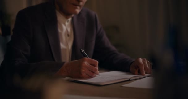 高齢のビジネスマンが日記で執筆し ビジネス戦略を計画しながら夜遅くにオフィスで — ストック動画