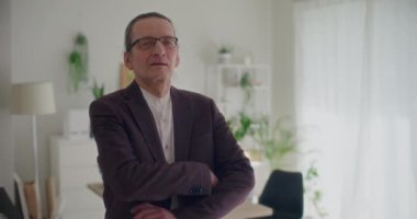 Ağır çekimde, şirket işyerinde kolları çapraz duran ve spor ceket giyen kendinden emin üst düzey bir erkek yöneticinin portresi.