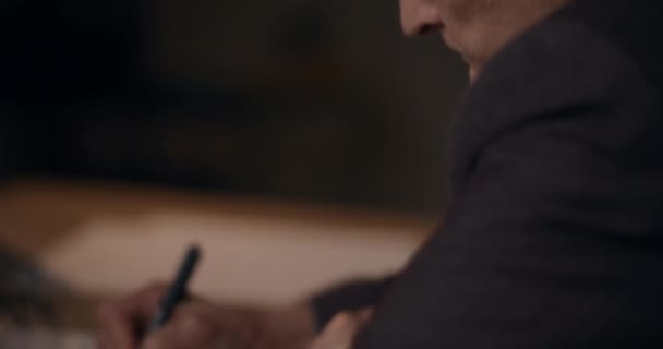 オフィスの深夜デスクに座っている間 シニアマネージャーが日記に書いたクローズアップショット — ストック動画