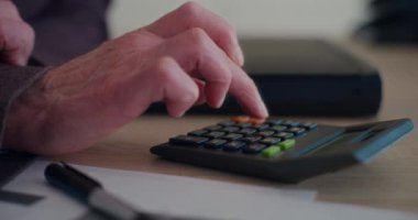 Kurumsal işyerindeki masalarda bütçe hesaplayan kıdemli işadamının eli