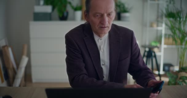 Ciddi Kıdemli Işadamı Şirket Işyerindeki Bilgisayarını Kullanırken Cep Telefonuyla Konuşuyor — Stok video