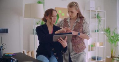 İş arkadaşlarıyla iş yerinde strateji planlarken dijital tablet üzerinde tartışan kendinden emin genç bayan girişimci