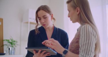 Kurumsal çalışma alanındaki toplantı sırasında dijital tablet üzerinde tartışan kendinden emin genç bayan girişimciler strateji planlarken