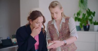 Kurumsal çalışma ortamında planlama yaparken akıllı telefondan tartışan kendinden emin genç bayan girişimciler.