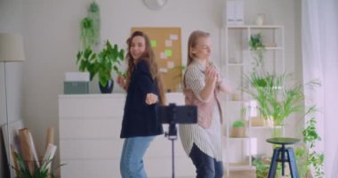 Evde tripodla akıllı telefondan dans videosu kaydeden mutlu genç kadın etkilerinin yavaş çekim görüntüleri.