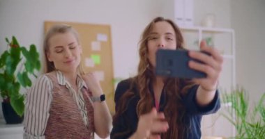 Neşeli genç kadınlar evdeki oturma odasında akıllı telefondan dans videolarını kaydediyor.
