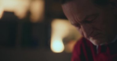 Düşünceli yaşlı adam loş bir evde, gecenin sessizliğinde hayat yolculuğuna ciddiyetle yansıyor.