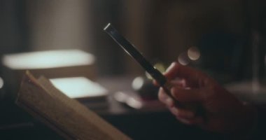 Yaşlı bir beyefendi gece vakti kitap okumaya dalmış, bir büyüteçle kitabını derinlemesine incelemiş, loş ışık altında bilgi arıyormuş.