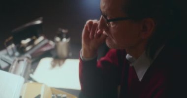 Düşünceli yaşlı adam loş bir evde, gecenin sessizliğinde hayat yolculuğuna ciddiyetle yansıyor.