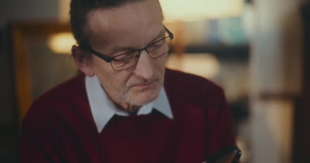 Ηλικιωμένος Κύριος Απορροφάται Στη Νυχτερινή Ανάγνωση Χρησιμοποιώντας Ένα Μεγεθυντικό Φακό — Αρχείο Βίντεο