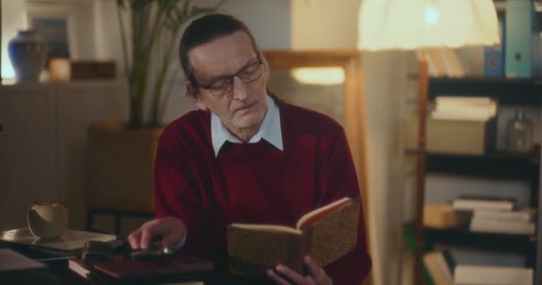 Anciano Caballero Inmerso Lectura Nocturna Cautivado Por Libro Bajo Luz — Vídeo de stock