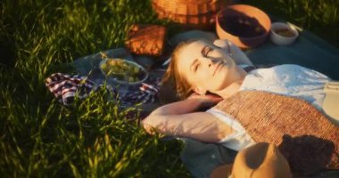 Gülümseyen bir kadının doğal güzelliğinin ortasında, rahat bir piknik battaniyesinde rahatlamaya alışması gibi boş zamanların esansını yakalayın.