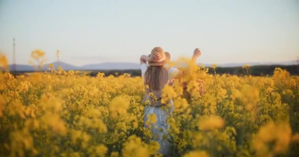 여자가 무성한 노란색 카놀라 필드를 실행으로 성공의 기쁨을 짜릿한 장면에서 — 비디오